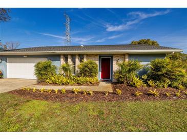 Charming home with a red front door, lush landscaping, and well-maintained lawn at 3298 Buckhorn Dr, Clearwater, FL 33761