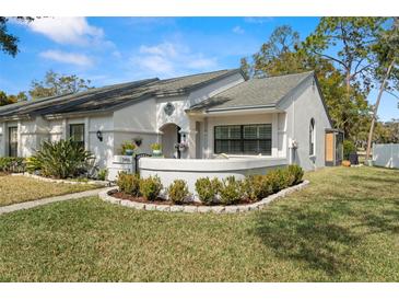 Charming single-story home featuring a beautifully landscaped front yard and a welcoming gated entryway at 3401 Killdeer Pl, Palm Harbor, FL 34685