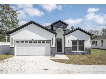 The exterior elevation of the home shows off the two-car garage and stone facade accents at 5351 71St N Way, St Petersburg, FL 33709