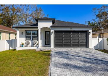 Charming one-story home featuring a gray brick driveway, manicured lawn, and a two-car garage at 1409 W Wood St, Tampa, FL 33604