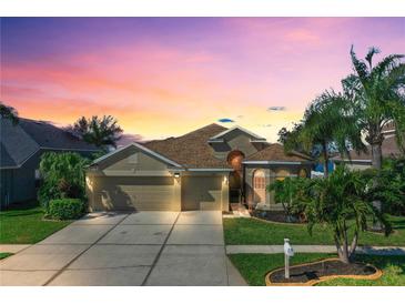 Charming single-Gathering home showcasing a well-manicured lawn, a three-car garage, and lush tropical landscaping at 1604 Mira Lago Cir, Ruskin, FL 33570