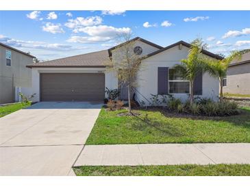 Charming single-story home with a well-manicured lawn, gray trim, and an attached two-car garage at 36642 Garden Wall Way, Zephyrhills, FL 33541