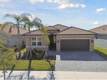 Well-maintained home featuring a paver driveway, a two-car garage and lush landscaping at 4911 Sienna Isles Ave, Wimauma, FL 33598