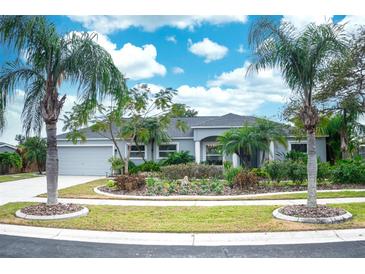 Charming home featuring a well-manicured lawn, lush landscaping, and beautiful palm trees at 6531 Clair Shore Dr, Apollo Beach, FL 33572