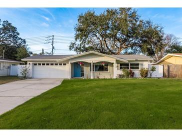 Charming single-story home featuring a well-manicured lawn and a welcoming blue front door at 932 Lexington Dr, Dunedin, FL 34698