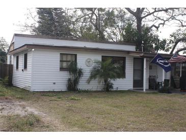 Charming single-story home with white siding and a cozy front porch, enhanced by flags and small palm trees at 10554 116Th N Ave, Largo, FL 33773