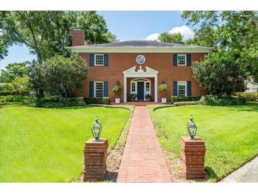 Two-story brick home with a manicured lawn and a brick walkway leading to the front door at 11806 Willow Point Way, Tampa, FL 33618