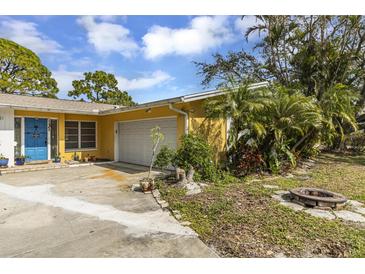 Charming yellow single-story home featuring a blue front door, attached garage, and well-kept landscaping at 1431 54Th Ne Ave, St Petersburg, FL 33703