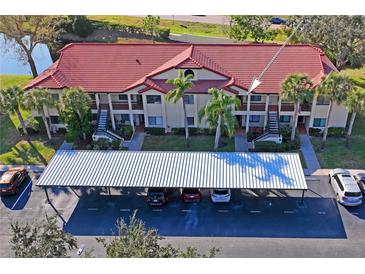 A sunny aerial view showcasing a condo complex with red tile roofs and ample parking space at 1801 E Lake Rd # 9G, Palm Harbor, FL 34685