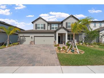 Charming two-story home with a three car garage, manicured lawn, and lovely landscaping at 3133 King Fern Dr, Wimauma, FL 33598