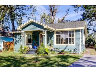 Charming blue home showcasing inviting front porch and mature trees at 1208 E Giddens Ave, Tampa, FL 33603