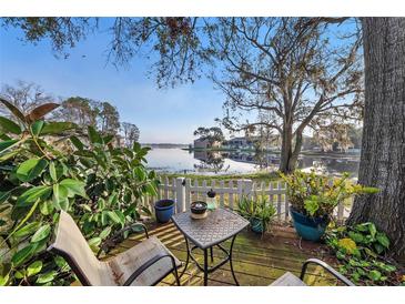 Backyard patio with seating overlooking the water, complete with landscaping, white picket fence, and large shade tree at 13733 Juniper Blossom Dr, Tampa, FL 33618