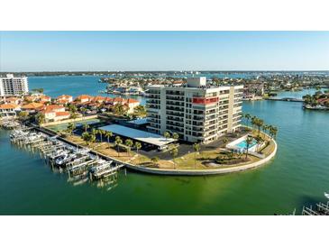 Stunning aerial view of the waterfront condo building with a private boat dock, tennis courts and swimming pool at 1651 Sand Key Estates Ct # 78, Clearwater, FL 33767