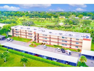 Aerial view of a four-story condo building with golf course views, covered parking, and manicured landscaping at 12200 Vonn Rd # 1305, Largo, FL 33774