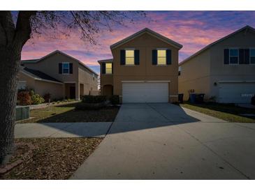 Two-story home with a front lawn and a two-car garage under a colorful, twilight sky at 12239 Fawn Brindle St, Riverview, FL 33578