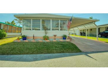 Charming home featuring a covered carport, brick-lined flower beds, and ample green lawn space at 18675 Us Highway 19 N # 320, Clearwater, FL 33764