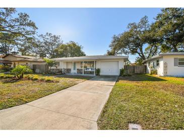 Charming one-story home featuring a manicured front yard and a paved driveway leading to an attached garage at 2008 Harvard Ave, Dunedin, FL 34698