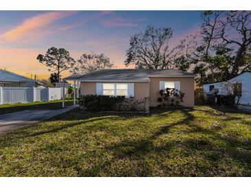 Inviting single-story home with a covered entryway set against a picturesque sunset backdrop with lush green lawn at 270 41St Ne Ave, St Petersburg, FL 33703