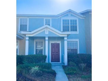 Two-story townhome featuring a blue exterior, well-maintained landscaping, and a welcoming front entrance at 3320 Broken Bow Dr, Land O Lakes, FL 34639