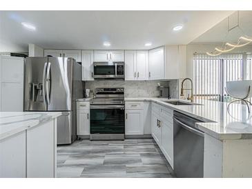 Bright kitchen features white cabinets, stainless steel appliances, and modern countertops at 4965 Puritan Cir # 401, Tampa, FL 33617