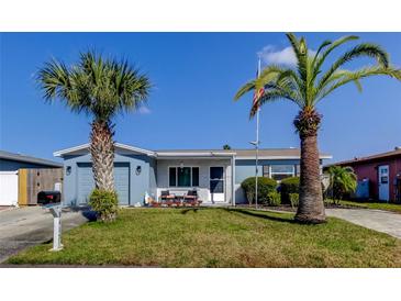 Charming single-story home with well-maintained lawn, front patio and blue exterior, shaded by two palm trees at 8417 Moulton Dr, Port Richey, FL 34668