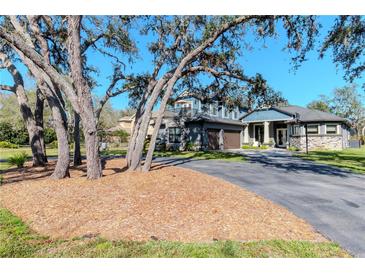 Charming two-story home with a stone facade, two-car garage, balcony, and manicured lawn at 9250 Rhea Dr, Odessa, FL 33556