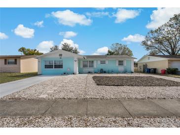 Charming single story home with light blue exterior, rock garden, and a concrete driveway at 1403 Coppertree Dr, Tarpon Springs, FL 34689