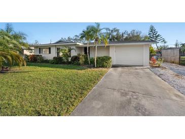 Charming single-story home featuring a lush green lawn, palm trees, and a convenient attached garage at 3218 Fauna St, Sarasota, FL 34235
