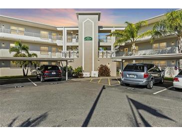 A condo building featuring assigned covered parking, and palm tree landscaping at 952 Virginia St # 108, Dunedin, FL 34698