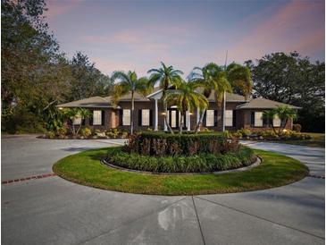 Stunning brick home boasts a circular driveway with lush palm trees and meticulously maintained landscaping at 9606 Braden Run, Bradenton, FL 34202
