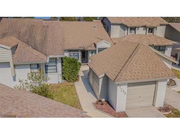 Neutral exterior showcasing a well-maintained home with a brown roof and attached garage at 11743 Rolling Pine Ln, Port Richey, FL 34668