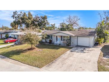 Charming single-story home featuring a well-manicured lawn and a long driveway, perfect for parking at 3624 Wiltshire Dr, Holiday, FL 34691