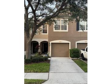 Townhouse showcasing a two-car garage, neutral-colored facade, and well-manicured landscaping at 4915 Pond Ridge Dr, Riverview, FL 33578