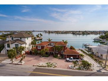 Waterfront home featuring a circular driveway, mature landscaping, and beautiful water views at 7013 Boca Ciega Dr, St Pete Beach, FL 33706