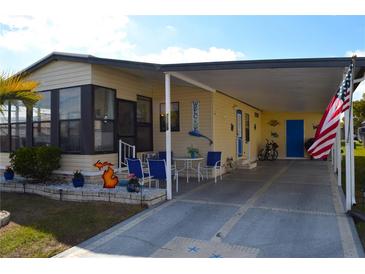 Charming tan home featuring covered parking, a seating area, and cheerful nautical decor at 7129 El Rancho Way, Zephyrhills, FL 33541