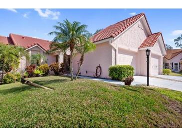 Charming single-story home with a well-maintained lawn, palm trees, and a vibrant red tile roof at 1157 Woodleaf Ct, Palm Harbor, FL 34684