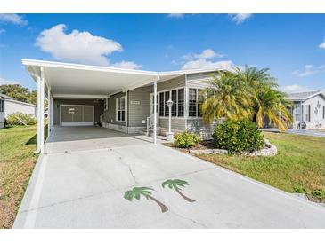 Charming home with covered parking, featuring mature palm trees and a well-maintained front yard at 36645 Kay Ave, Zephyrhills, FL 33542