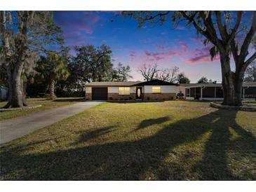Charming single-story home features a stone facade, well-manicured lawn, mature trees, and an attached garage at 5602 Bay Blvd, Port Richey, FL 34668