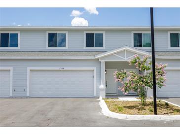 New townhouse exterior featuring a one-car garage, white trim, and a blooming decorative tree at 7529 62Nd N Way, Pinellas Park, FL 33781