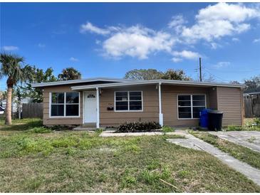 Charming single-story home with tidy landscaping and mature palm trees under a partly cloudy blue sky at 7563 Meadowlawn N Dr, St Petersburg, FL 33702