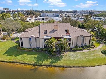 An aerial view of a condo building with well-maintained landscaping, situated on a pond and featuring a red door at 10263 Gandy N Blvd # 209, St Petersburg, FL 33702