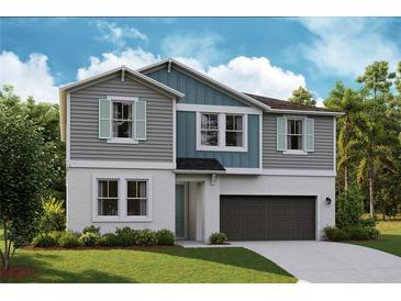 Charming two-story home featuring a two-car garage, well-manicured lawn, and stylish gray and blue siding at 12148 Cattleside Dr, Riverview, FL 33579