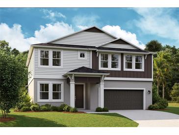 Charming two-story home with gray and white color scheme and a well-manicured front yard at 14441 Meadow Bird Ave, Riverview, FL 33579