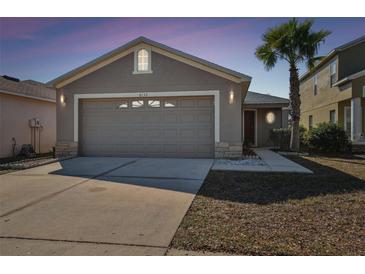 Charming single Gathering home with a two car garage, gray siding, and palm tree in the front yard at 8133 Canterbury Lake Blvd, Tampa, FL 33619
