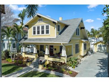 Charming two-story yellow home with a welcoming front porch and lush, tropical landscaping in a desirable neighborhood at 445 13Th Ne Ave, St Petersburg, FL 33701