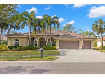 Charming home featuring a tile roof, arched entryway, manicured landscaping, and a spacious three-car garage at 4564 Juniper Dr, Palm Harbor, FL 34685