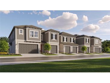 Exterior of new townhomes with neutral color palette, garages, and landscaping on a sunny day at 10807 Fort White Ct, Tampa, FL 33647