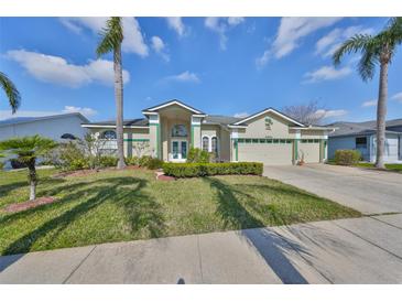 Charming single-story home with lush landscaping, palm trees, and a two-car garage at 13024 Prestwick Dr, Riverview, FL 33579