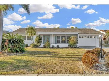 Charming single-story home with a well-maintained lawn and mature landscaping at 1740 Coco Palm Cir, Sun City Center, FL 33573