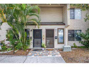 Townhouse exterior featuring two front doors with screens and decorative stone walkway and tropical landscaping at 6303 23Rd N St, St Petersburg, FL 33702